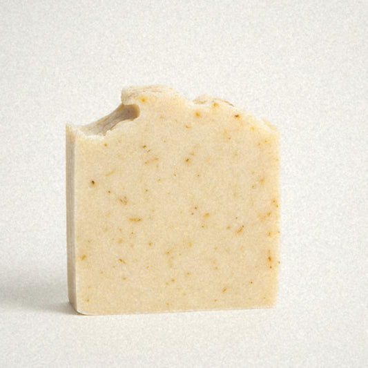 Sunshine Yuzu goat milk soap bar, cream with golden flecks, on white