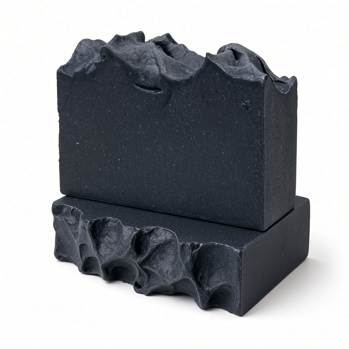 Two charcoal goat milk soap bars stacked, showing the textured black top
