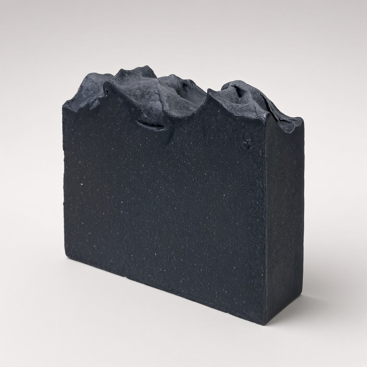 Charcoal goat milk soap bar standing upright on a light gray background
