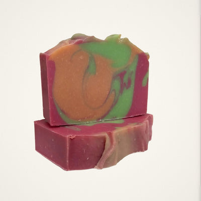 Two Apple Mango Tango goat milk soap bars with pink, orange and green swirls on a white background