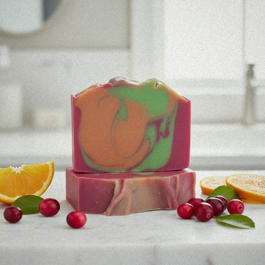 Apple Mango Tango goat milk soap on marble with cranberries and orange slices