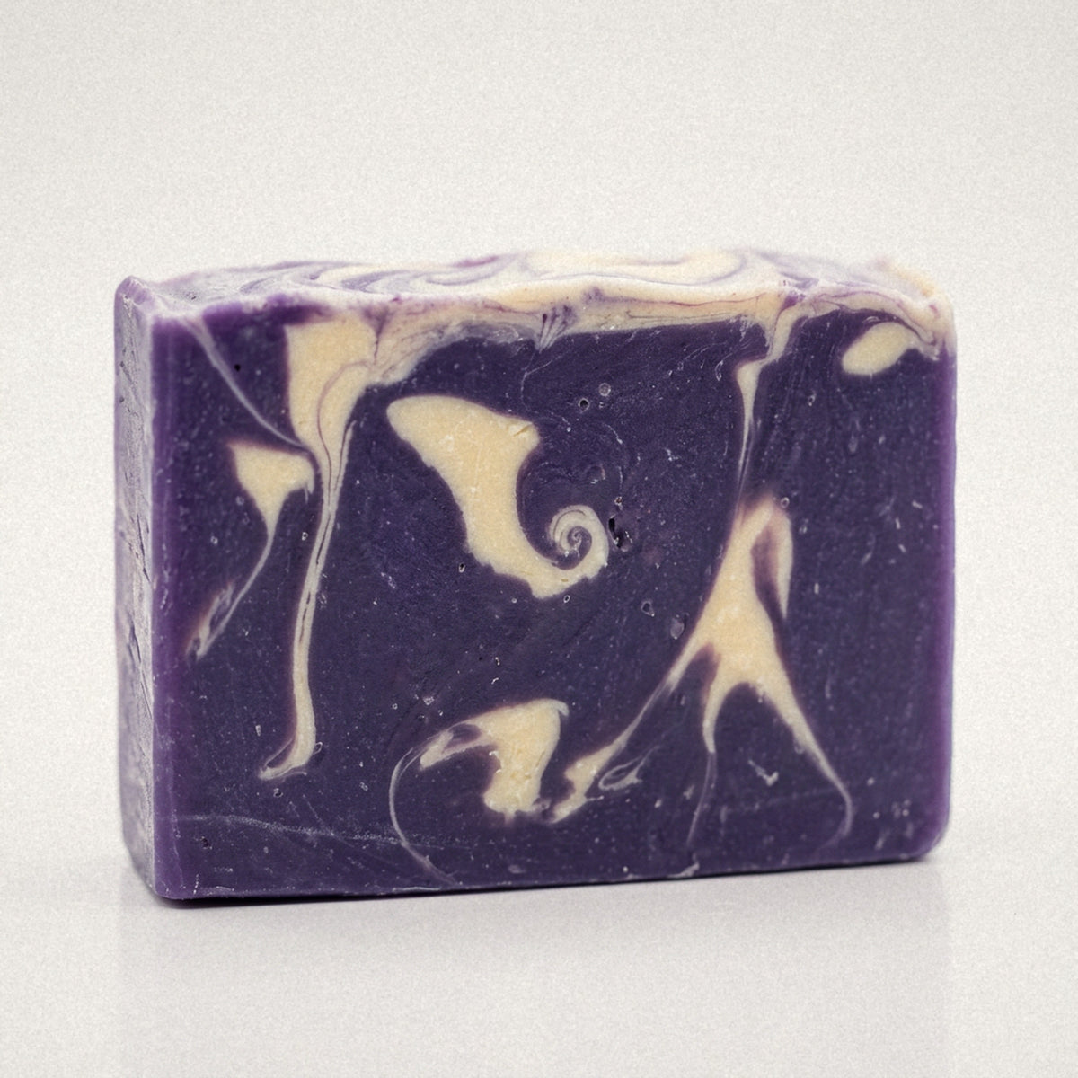 Lavender goat milk soap bar with purple and cream swirls on a white background