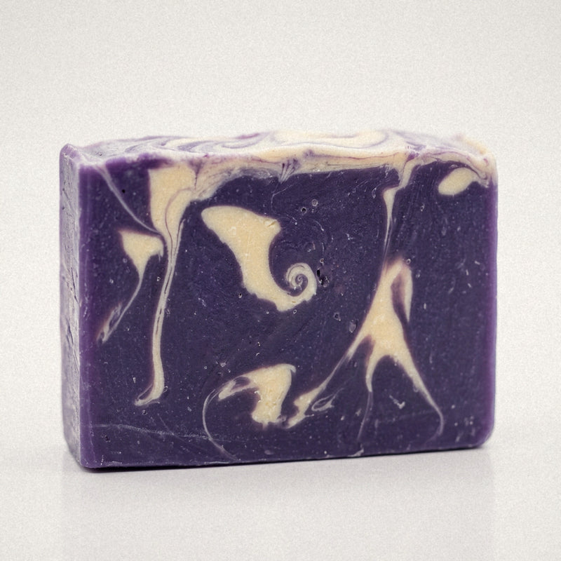 Lavender goat milk soap bar with purple and cream swirls on a white background