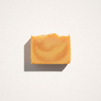 Mango Tangerine goat milk soap bar with orange and cream swirls on a white background