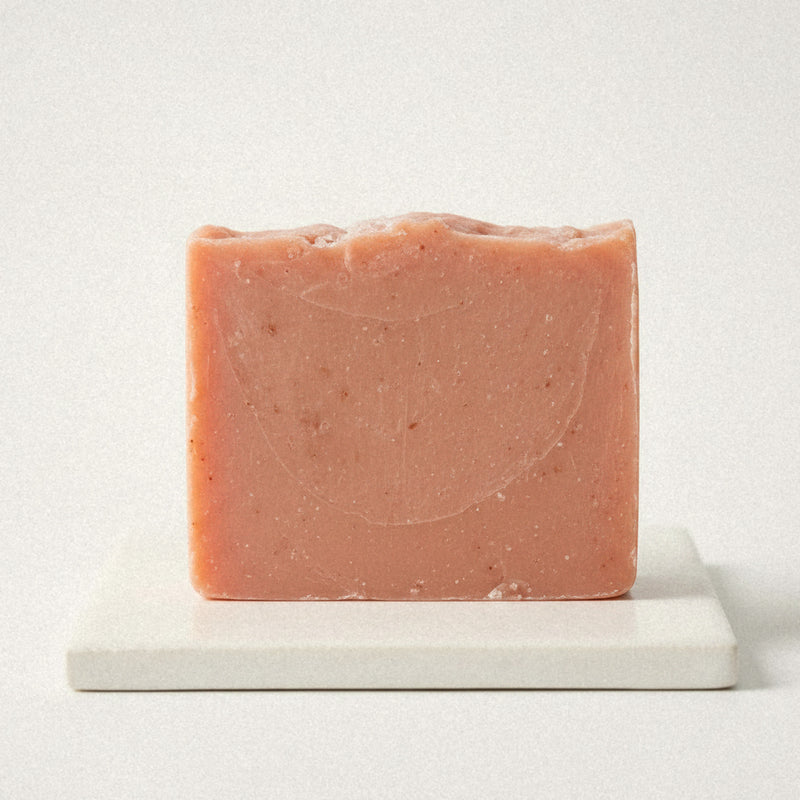 Sea Salt Blossom goat milk soap bar, coral pink, on a white stone dish