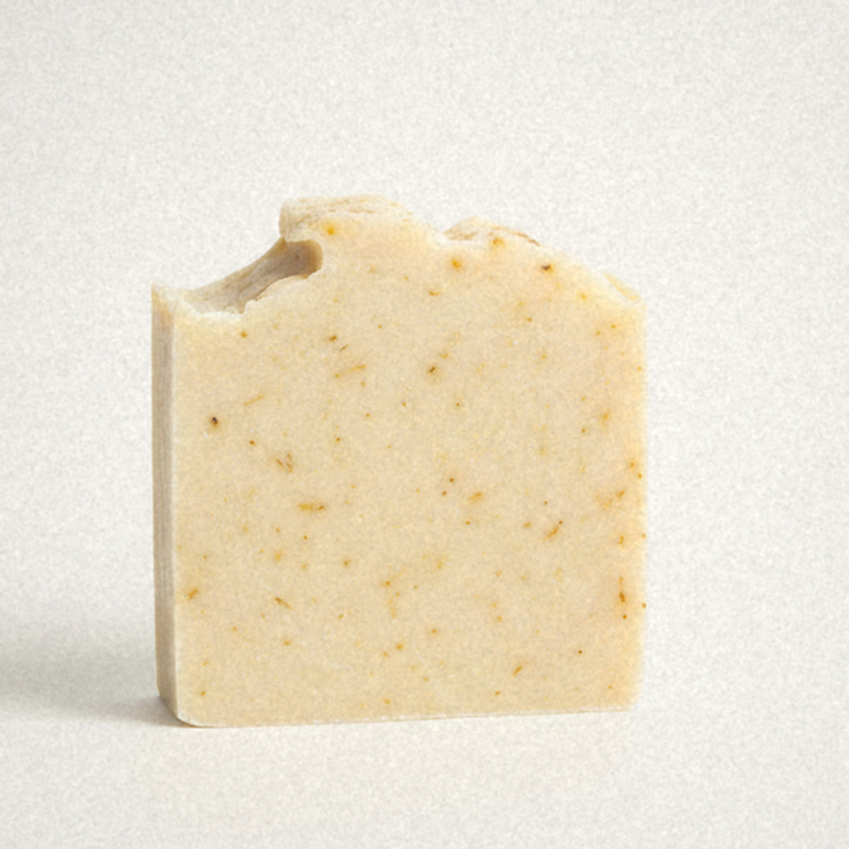 Sunshine Yuzu goat milk soap bar, cream with golden flecks, on white
