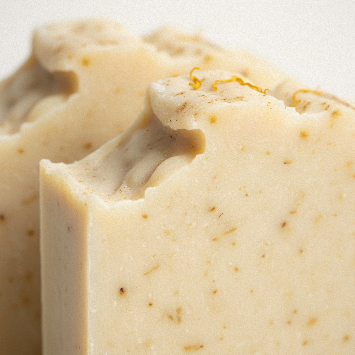 Close-up of Sunshine Yuzu goat milk soap, a cream bar flecked with golden calendula petals