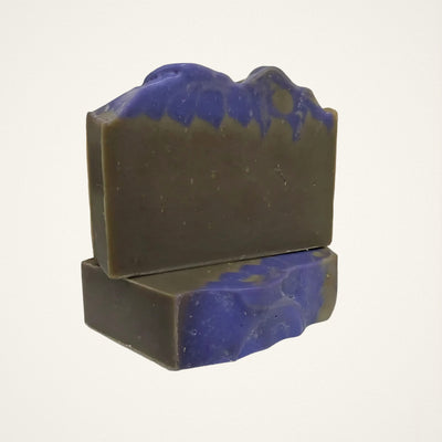 Two Vanilla Fig goat milk soap bars, olive with indigo top and base, on a white background