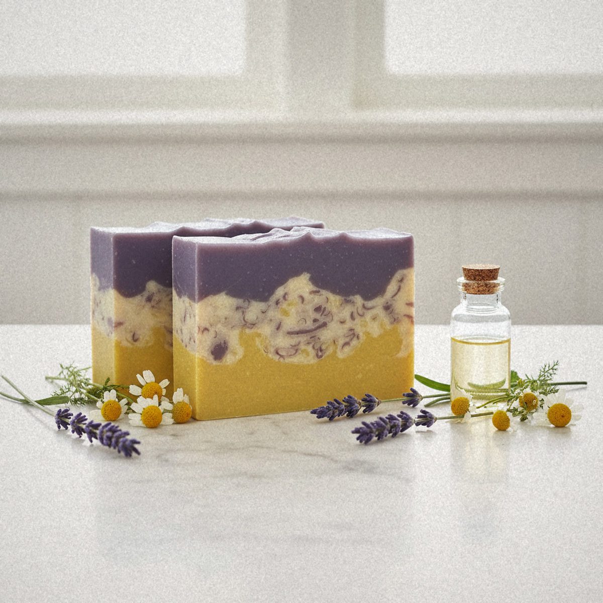 Two Wildberry goat milk soap bars on marble with lavender, chamomile and a small glass bottle