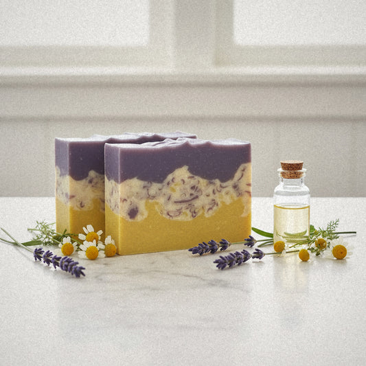 Two Wildberry goat milk soap bars on marble with lavender, chamomile and a small glass bottle
